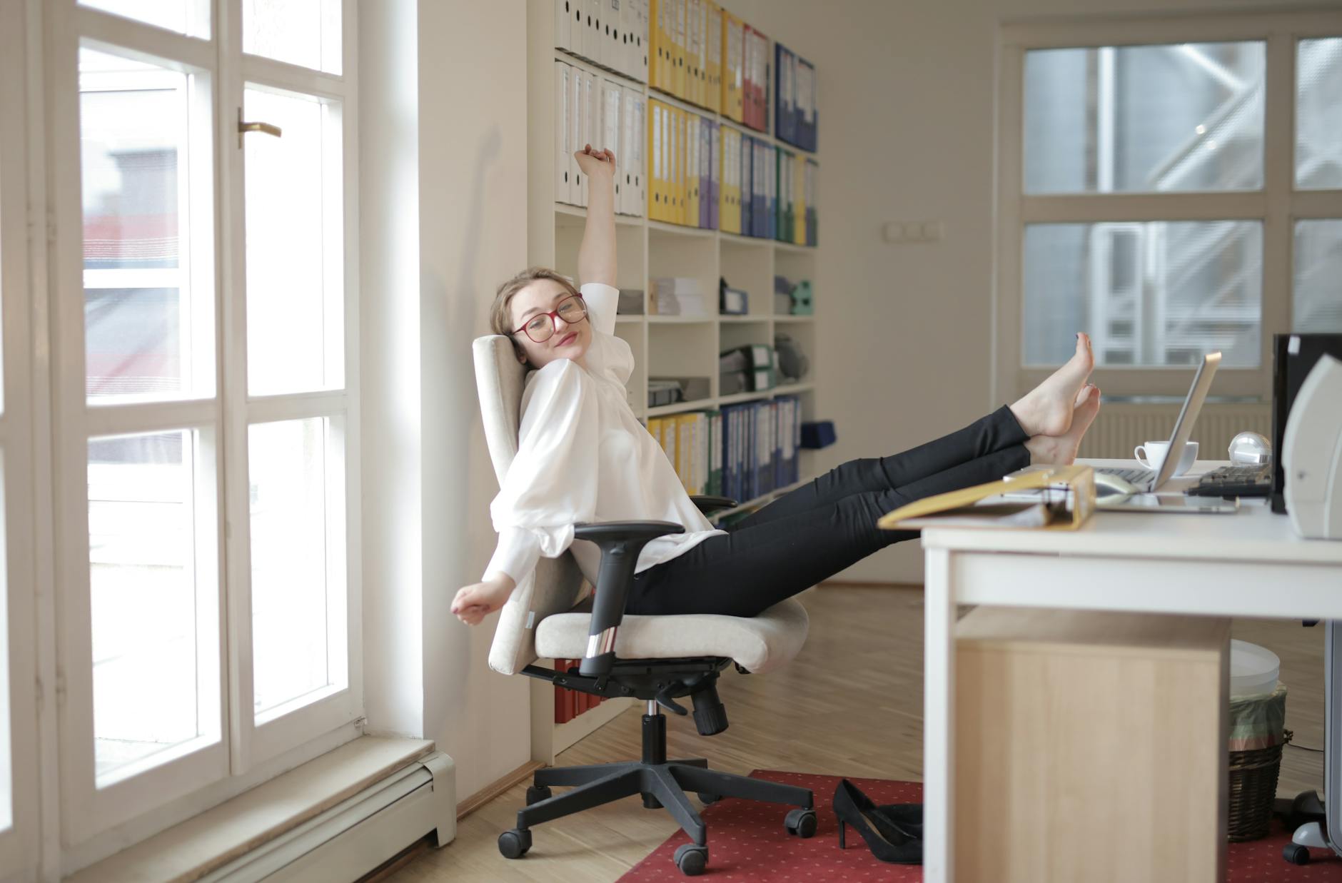 A serene person sitting in an office chair doing a gentle stretch.